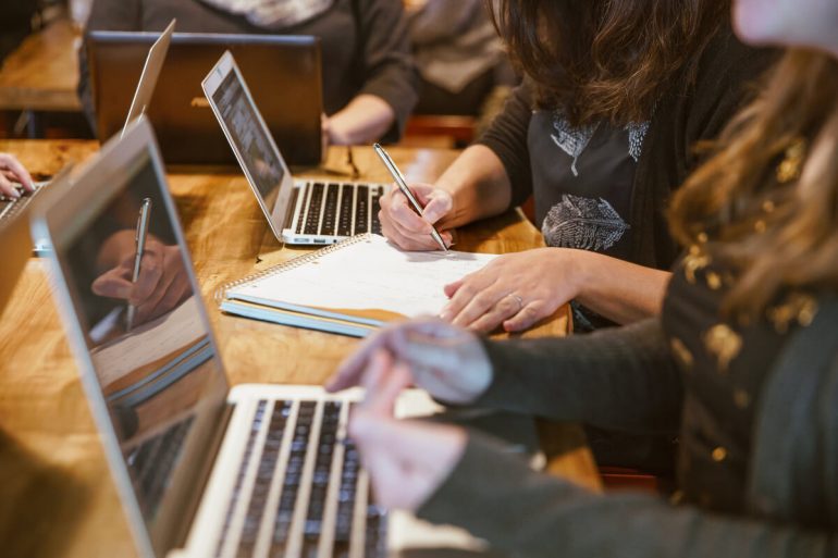 stock image of a computer coding workshop with female hands visible and computers, no faces