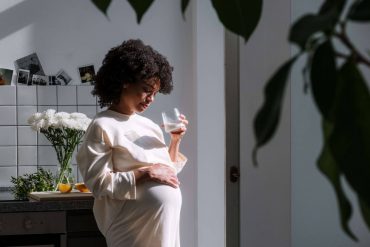 Pregnant woman in white dress touching belly