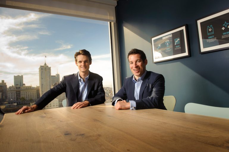 AppDirect's co-founders and co-CEOs smiling at a table