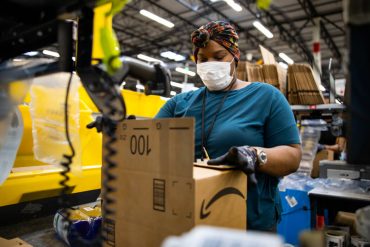 Amazon worker in fulfillment centre packing box