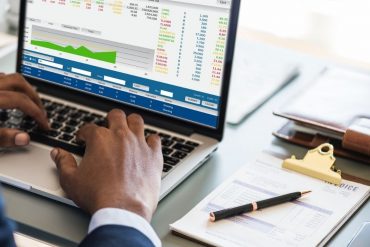 A person typing into a laptop with its screen showing data marketing analytics.