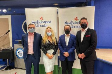 Premier Andrew Furey standing next to Sarah Murphy, Ed Clarke, and Gregory Smyth in front of the Newfoundland and Labrador banner.