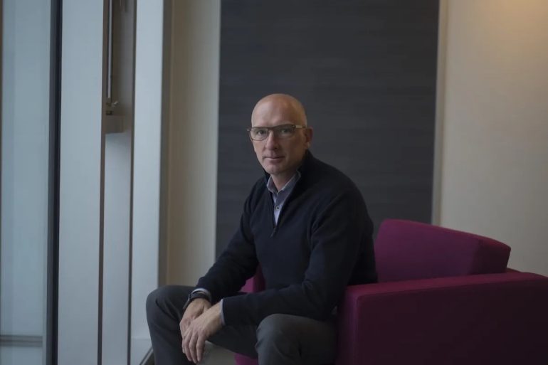 Mike Wessinger, CEO of PointClickCare, sitting on a chair.