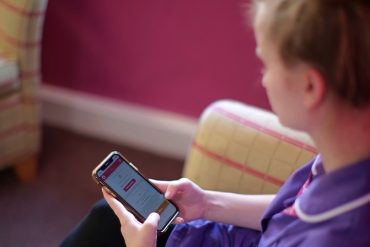 Lady in a purple shirt accessing Cera Healthcare from her phone.