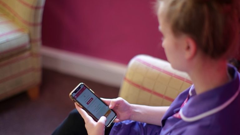 Lady in a purple shirt accessing Cera Healthcare from her phone.
