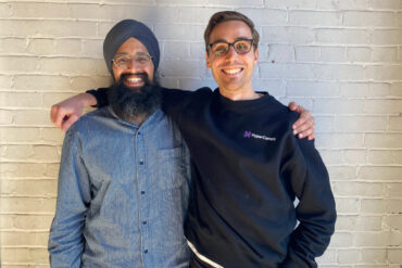HyperComply co-founders Amar Chahal and Cody Wright stand with their arms around each others' shoulders.