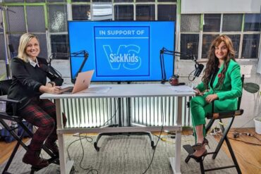 Fatima Zaidi and Amber Mac sitting at a table at the Tech4SickKids auction.