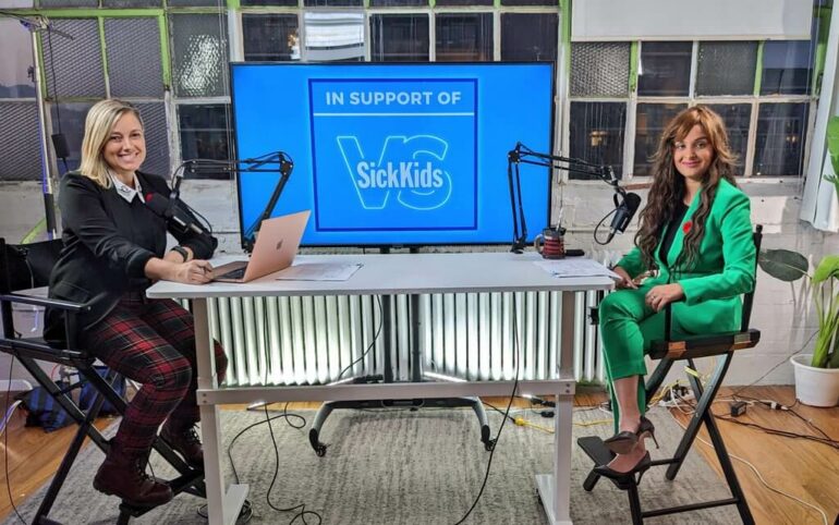 Fatima Zaidi and Amber Mac sitting at a table at the Tech4SickKids auction.