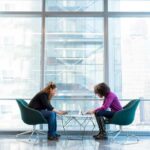Two women in a sky high building working on their laptops