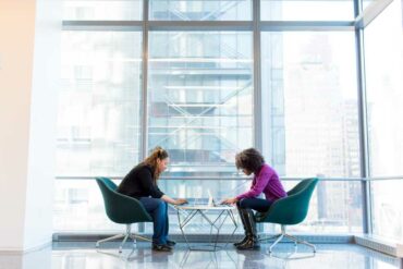 Two women in a sky high building working on their laptops