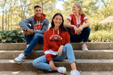 Three people wearing sporting merchandise.