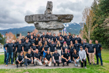 the VRIFY team in matching black t-shirts with an inukshuk in the background