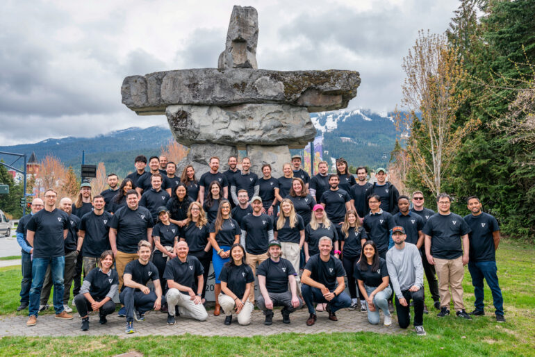 the VRIFY team in matching black t-shirts with an inukshuk in the background