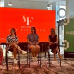 Four women speak on a panel with a red backdrop that says The Firehood