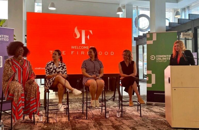 Four women speak on a panel with a red backdrop that says The Firehood