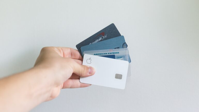 A hand holding four payment cards in a fan fashion.