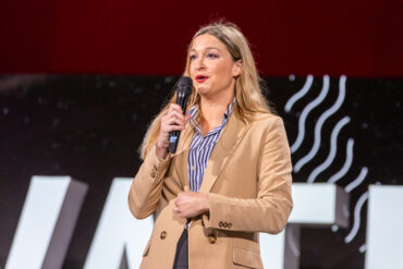 Kara LeBlanc on the podium speaking at Elevate