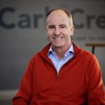 Jacob Homiller, newly-appointed CarbiCrete CEO is front and center. He is smiling. The CarbiCrete logo is on a wall in the background