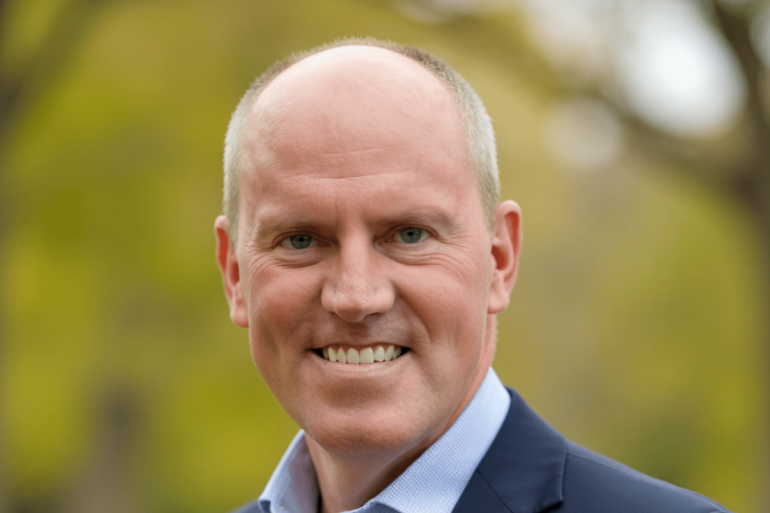 portrait outdoors of Bob Smith, a bald white man wearing a suit