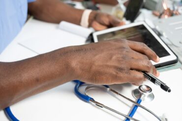 a close-up of a hand on a laptop with stethoscope