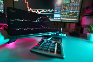A desk with a keyboard and a monitor graphic tablet crypto currency stock bars calculator