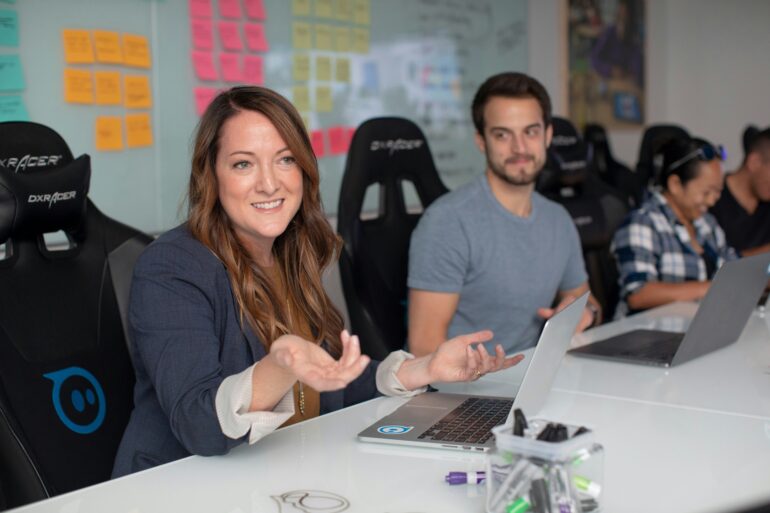 lady in blazer in front of computer and wall with sticky notes