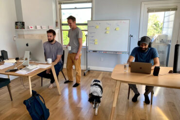 Three men work at computers