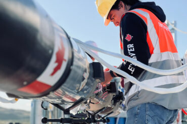 A man in a high-res vest and hardhat works on the Nordspace rocket