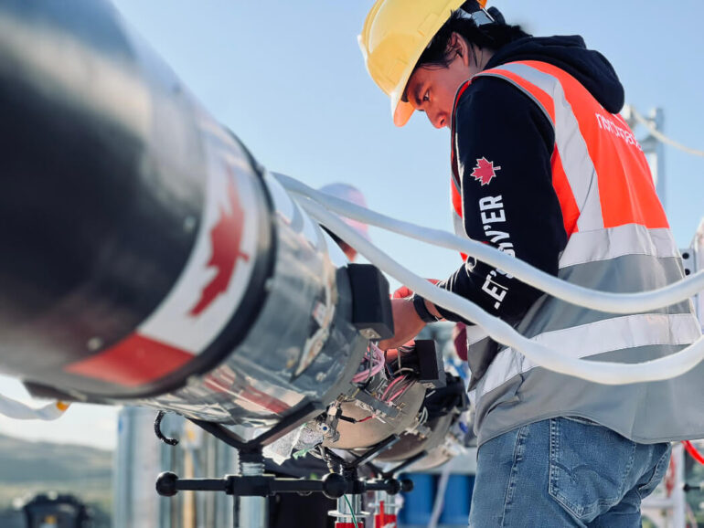 A man in a high-res vest and hardhat works on the Nordspace rocket