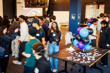 A young woman throws a thumbs up amid a crowd of people at Waterloo Tech Week