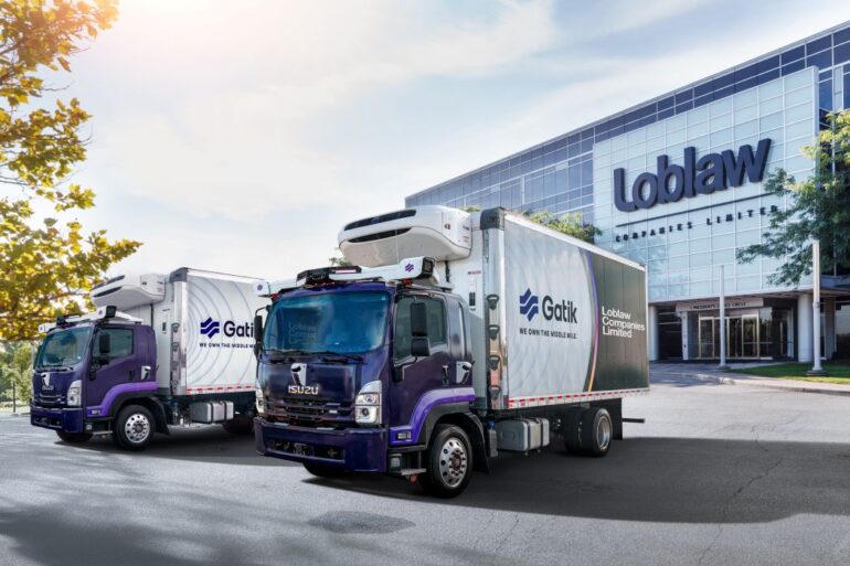 Two driverless trucks in front of a Loblaw store.