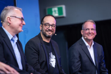 Nesto CEO Malik Yacoubi sits on stage with two other unidentified man.