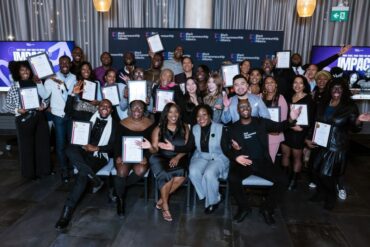 A large group of Black entrepreneurs sit together, smiling at the camera