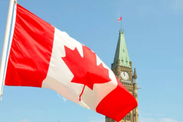 The Canadian flag blows in the wind with Parliament hill in the background