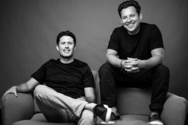 A black-and-white portrait of Harley Finkelstein and David Segal sitting casually on a couch.
