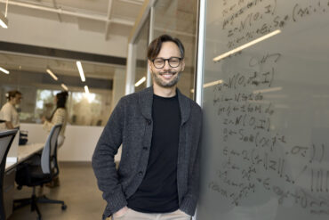 Hugo Larochelle leans against a white board.