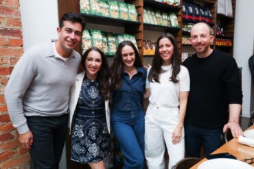 A group of people stand arm-in-arm, smiling.