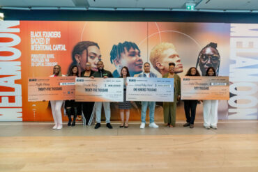 A group of black founders stand side-by-side showing off novelty checks.