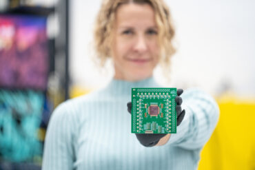 A woman holds computer hardware up to teh camera