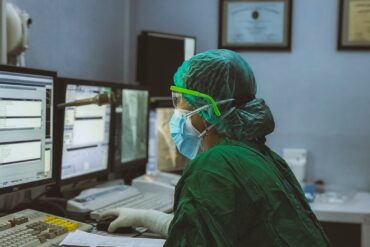 A clinician in scrubs using a computer.