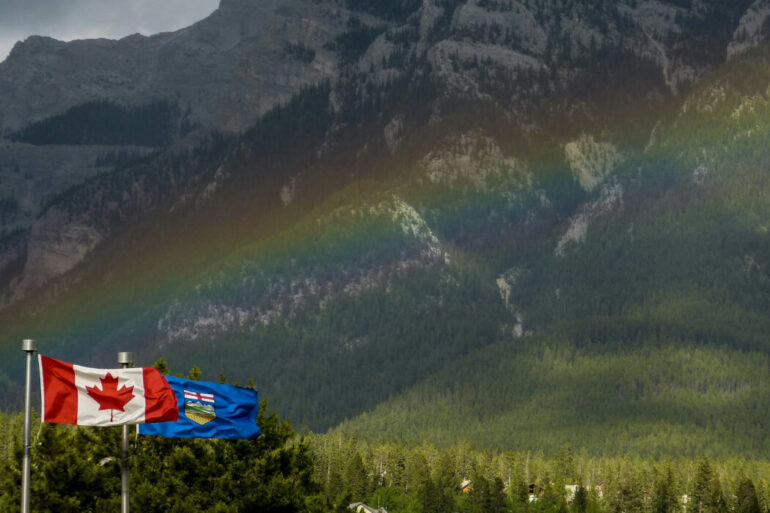 And Alberta and Canada flag in front of a rainbow.