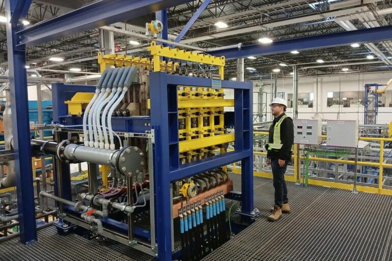 A man stands beside NORAM machinery