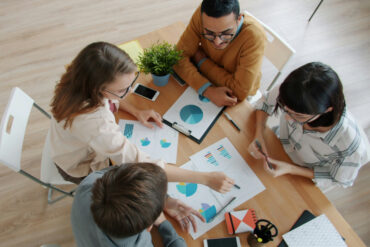 A group of people sitting around a small table working on a project.