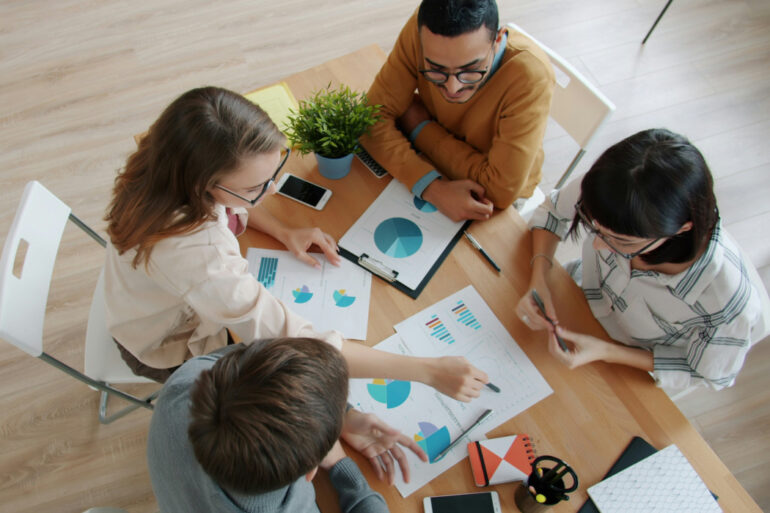 A group of people sitting around a small table working on a project.